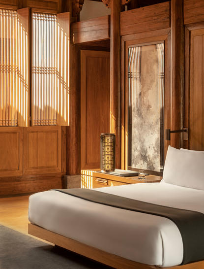 Minimalist principal bedroom at Amanyangyun with wooden screens, neutral tones and a cylindrical white ottoman.