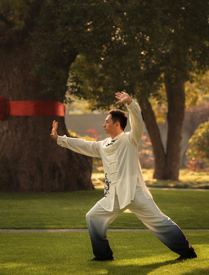 Woman practising tai chi on the lawn at Amanyangyun at sunset.