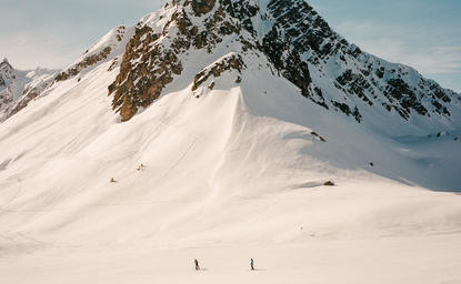Snowy Alpine slopes at Aman Le Mélézin resort in France, with skiers descending the mountainside.