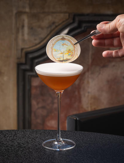 Bartender garnishing Armonia signature cocktail at Aman Venice with citrus peel.