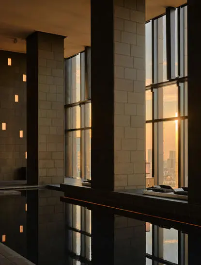 Spa wellness area at Aman Tokyo with tall windows casting geometric light patterns on dark surfaces.