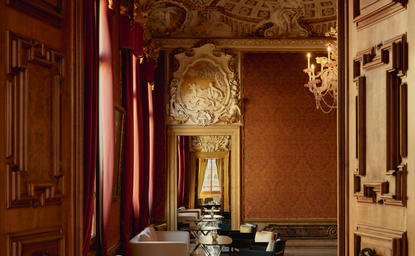 Bar at Aman Venice with warm terracotta walls, ornate gold detailing, and classical architectural elements.