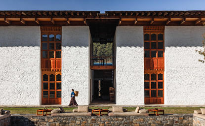 Amankora Bumthang Lodge exterior with traditional Bhutanese architecture featuring white walls and dark wooden columns.