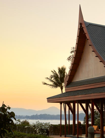 Villa pavilion at Amanpuri resort at sunset, with tropical palm trees and coastal views.