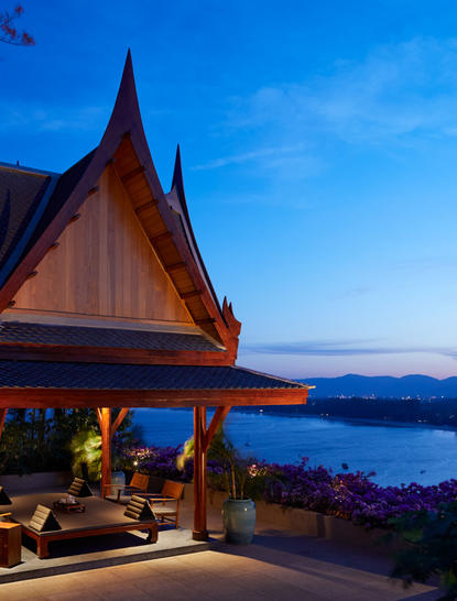 アマンプリ・リゾートの木造寺院風建築が、夜明けの湖と山々を背景に佇む。