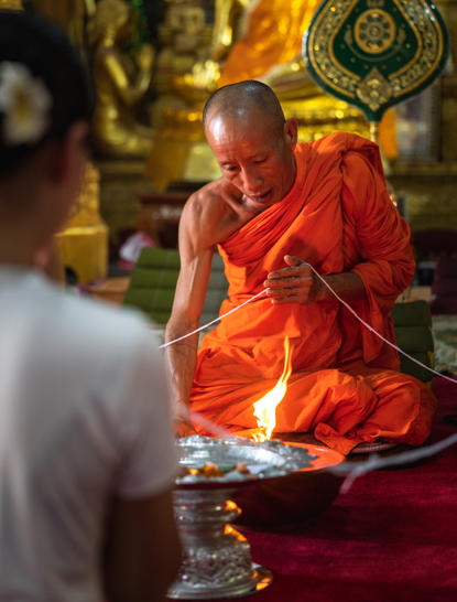 Buddhist monk in saffron robes performing a blessing ceremony at Amantaka.