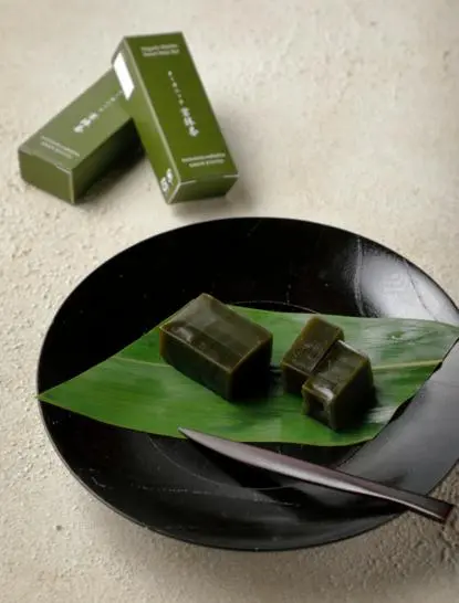 Matcha sweet bean bars arranged on a black plate at Aman Kyoto, with green packaging displayed behind.