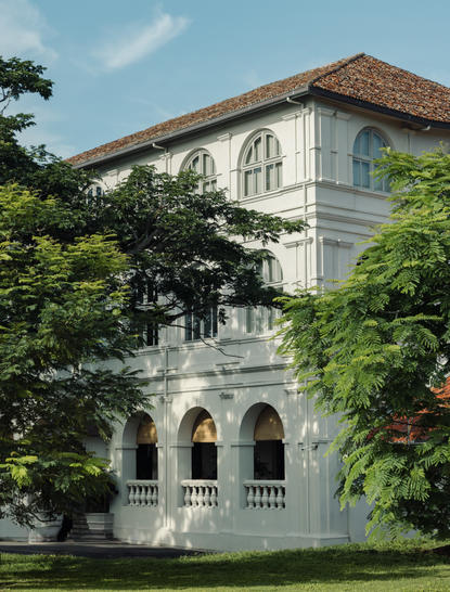 Colonial-era mansion at Amangalla with white facades and arched windows, framed by lush greenery.