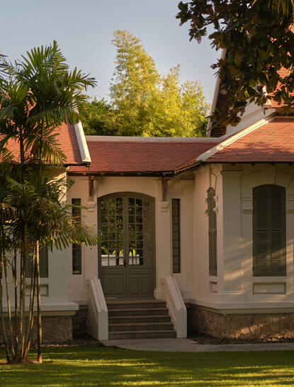 Khan Pool Suite entrance at Amantaka, featuring terracotta roof and stone exterior among lush gardens.