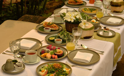 Shared breakfast plates and fresh salads arranged on a dining table at Amantaka, Laos.
