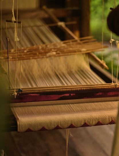 Close-up of traditional Laotian silk weaving loom at Amantaka, showing wooden threads and textile craftsmanship.