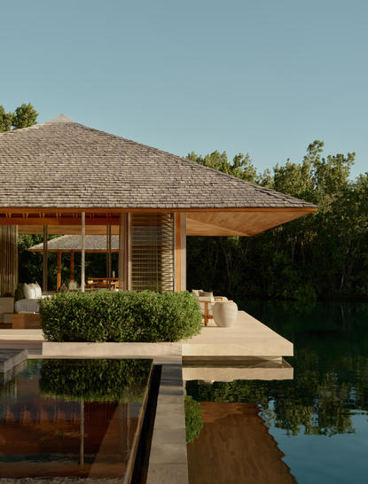 Amanyara villa pavilion with thatched roof overlooking still water at dusk.