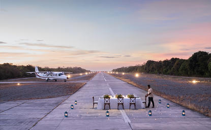 Private dining setup on Amanpulo's seaplane runway at sunset, resort in the Philippines.