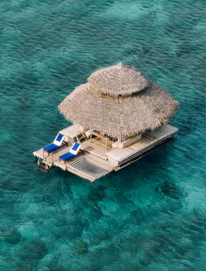 アマンプロのリゾートにある浮かぶカワヤンバーを上空から撮影した写真。ターコイズブルーの海に浮かぶ茅葺き屋根の建物。