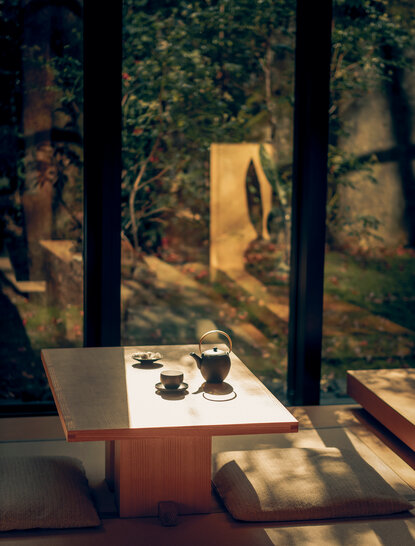 Afternoon tea service at a table with garden views through tall windows at Aman Kyoto.