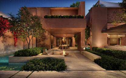 Amanjena residence exterior at dusk, with warm lighting illuminating terracotta walls and manicured gardens.
