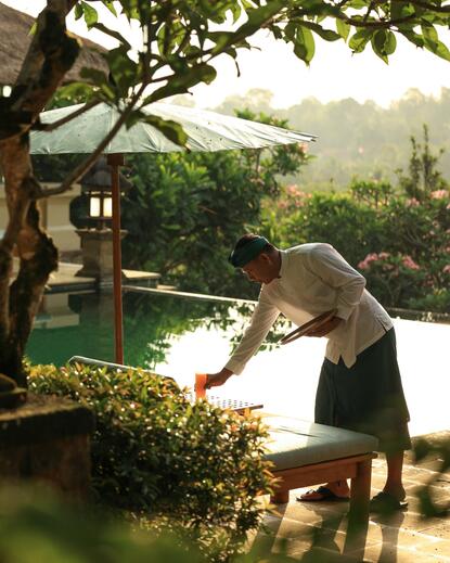 Family member reading by the river at Amandari, Bali, Indonesia.