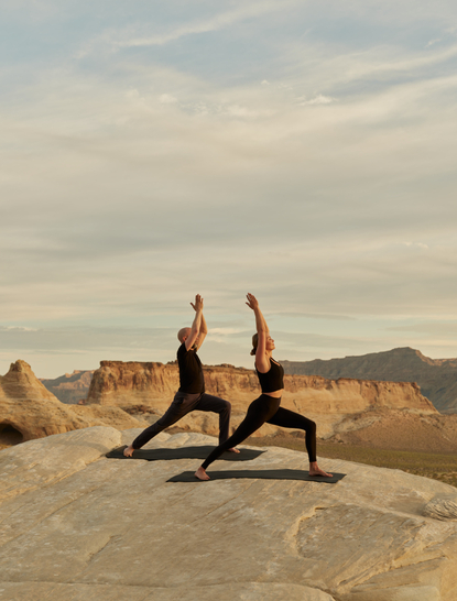 Deux femmes pratiquent le yoga sur les rochers du désert à Amangiri resort.