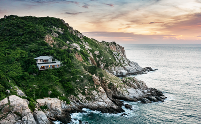 Aerial view of a one-bedroom ocean pool residence at Amanoi perched on a clifftop overlooking the sea and mountains.