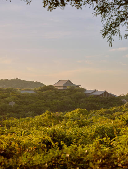 Amanoi's main pavilion exterior set amongst verdant Vietnamese landscape and distant mountains.