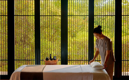 Woman receiving massage at Amanoi wellness spa, with golden screens in background.