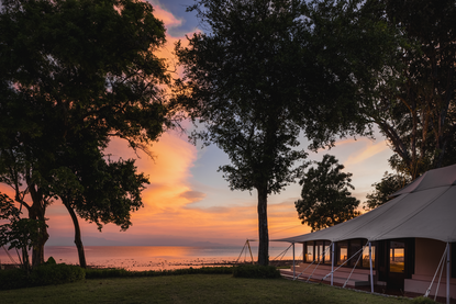 Ocean tent at Amanwana with sunset view across the sea, framed by tropical trees.