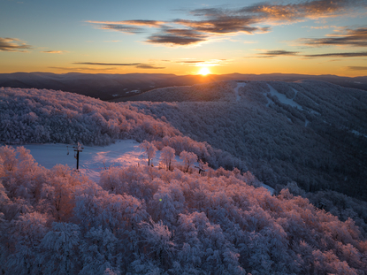 Amanecer sobre paisaje montañoso nevado, vista aérea en Aman New York.