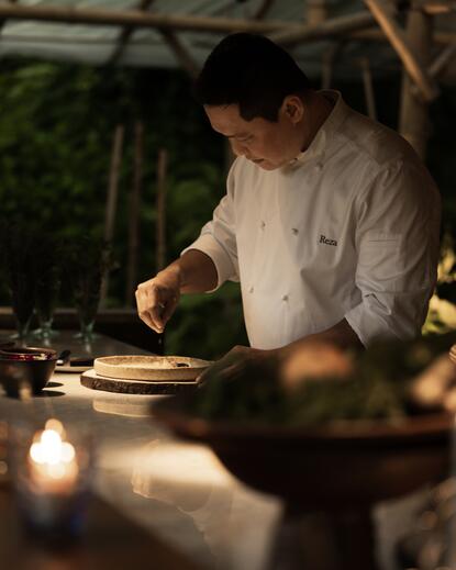 Chef Reza preparing a dish at the chef's table in the joglo sawah dining venue at Amanjiwo.