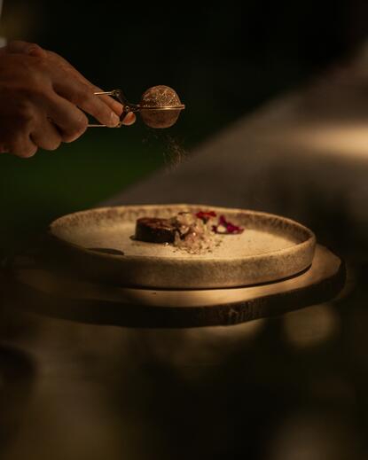 Chef Reza grates nutmeg over a dish at Amanjiwo's chef's table in the joglo overlooking the rice fields.