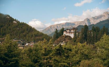 Amankora perched on a forested hillside in Paro valley, Bhutan, with mountains beyond.