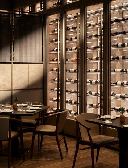 Wine library at Aman New York with floor-to-ceiling wooden shelving and seating area.