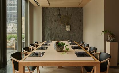 アマン ニューヨークのプライベートダイニングルーム。木製テーブルに設置された席から、都市の景観が見える。