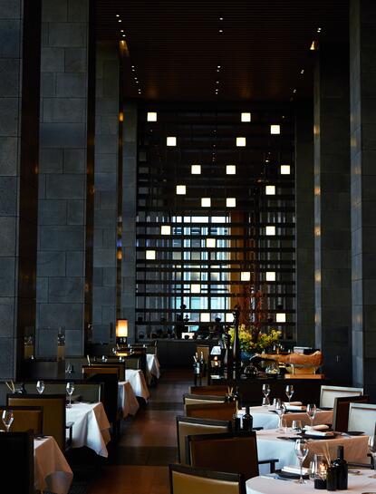 Aman Tokyo's dining room with soaring ceilings, geometric lighting installation, and contemporary architectural design.