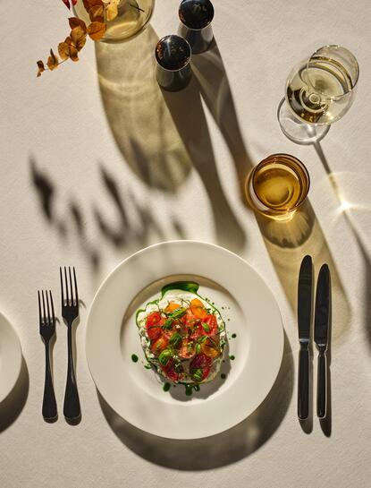 Burrata salad plated at Aman Venice, surrounded by wine glasses and formal place setting.
