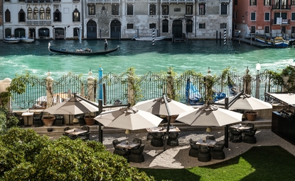 Terrasse de jardin surplombant le Grand Canal à Aman Venice, avec transats et parasols.