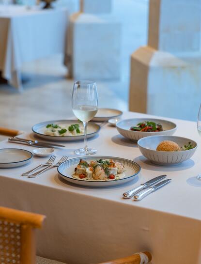 Arva dining venue at Amankila resort, with multiple dishes and place settings overlooking the ocean.