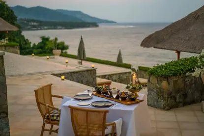 Table dressée sur la plage avec vue sur la baie à Amankila, resort à Bali, Indonésie.
