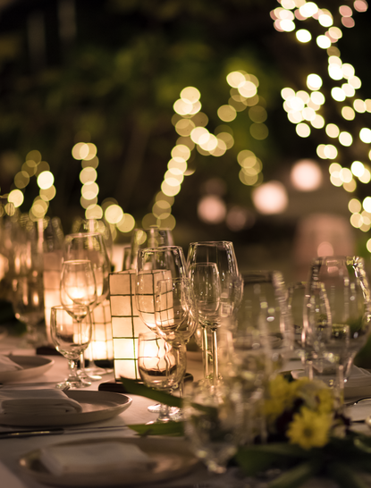 Tavolo allestito per una celebrazione notturna ad Amanpulo, con candele e bicchieri illuminati.