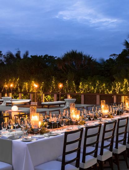 Tavoli per cena illuminati al tramonto nella clubhouse West Villa di Amanpulo, resort nelle Filippine.