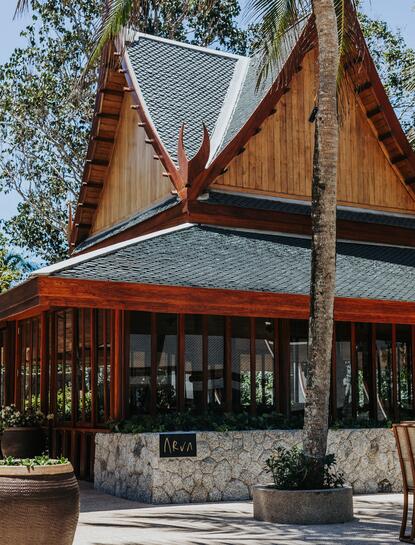 Holzgebäude mit traditionellem Dach im Amanpuri Resort, Thailand, Außenansicht.