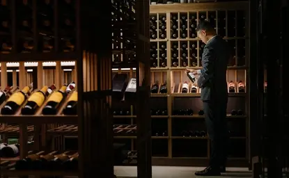 养云安缦酒店的葡萄酒窖内部，展示排列整齐的酒瓶和木质酒架，灯光温暖柔和。