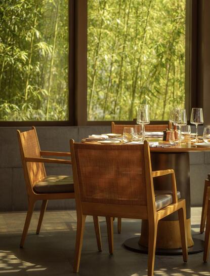 Dining table and chairs at Amanyangyun with forest views through large windows.