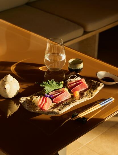 アマンゾイ リゾートのナマ寿司レストランで、金色の照明に照らされた寿司盛り合わせ。