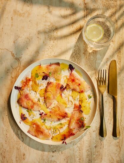 Yellowtail crudo dish at Amanpuri resort, served on a white plate with citrus and garnish.