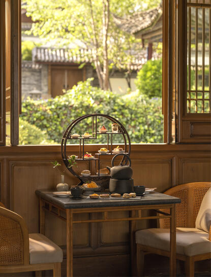 大研安缦度假村的木制门框景观,透过开放式门廊眺望绿意庭园与传统建筑。