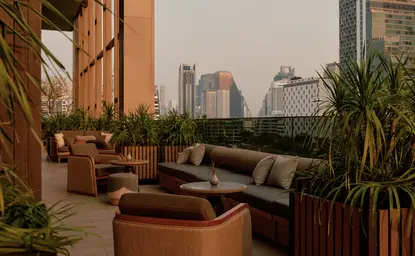 Bar seating area at Aman Nai Lert Bangkok with city views and potted plants.