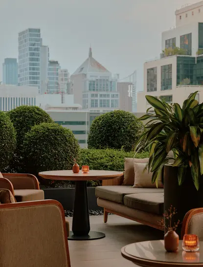 Aman Lounge seating area with city views of Bangkok's skyline and temples in the distance.