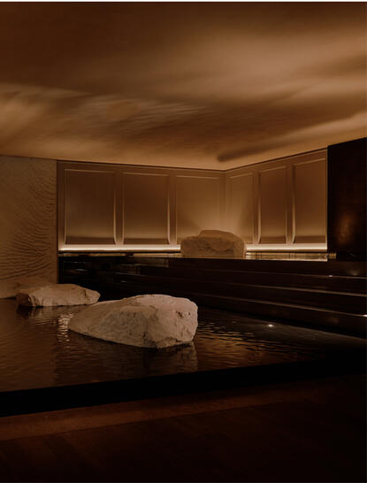 Spa treatment room at Aman Nai Lert Bangkok with warm lighting and massage bed.