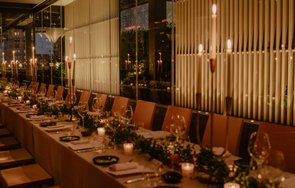 Elegant dining table set for celebration at Aman New York, with warm lighting and floral centerpieces.