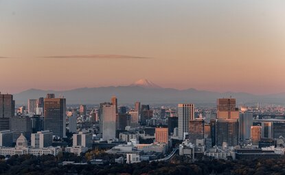 Tokyo skyline at dusk, with city buildings silhouetted against a soft amber sky, as seen from Aman Tokyo.